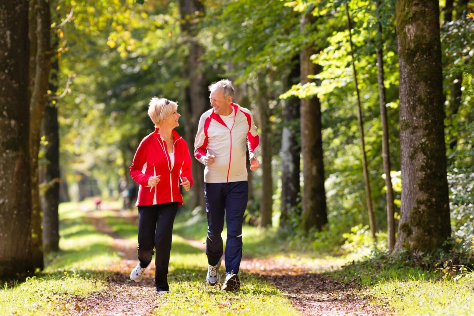Two older women walking down a path in the woods.