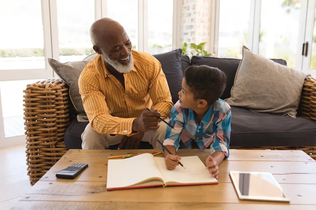 grandfather helping grandson with math homework in the sunroom of house